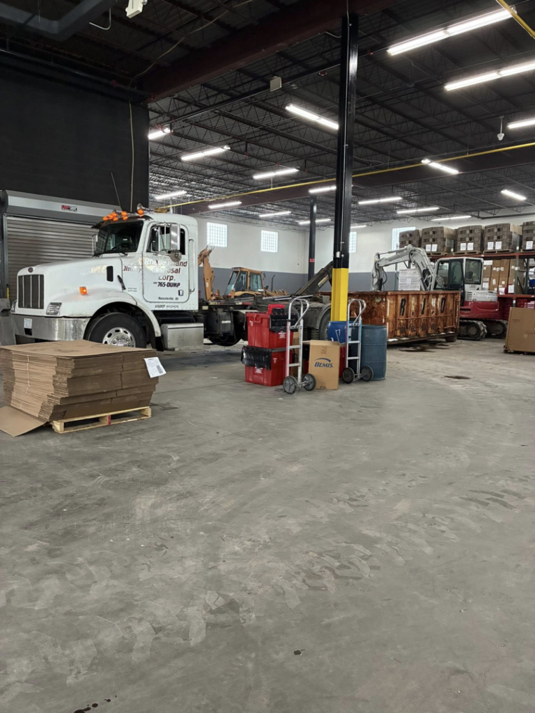 A Rhode Island Disposal roll-off truck and dumpster inside a garage, ready for junk removal services in Providence, RI.