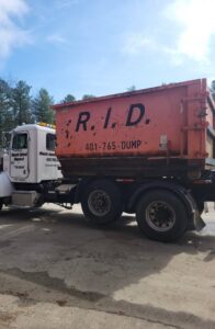 A Rhode Island Disposal truck carrying a large orange roll-off dumpster, ready for junk removal in Providence, RI.