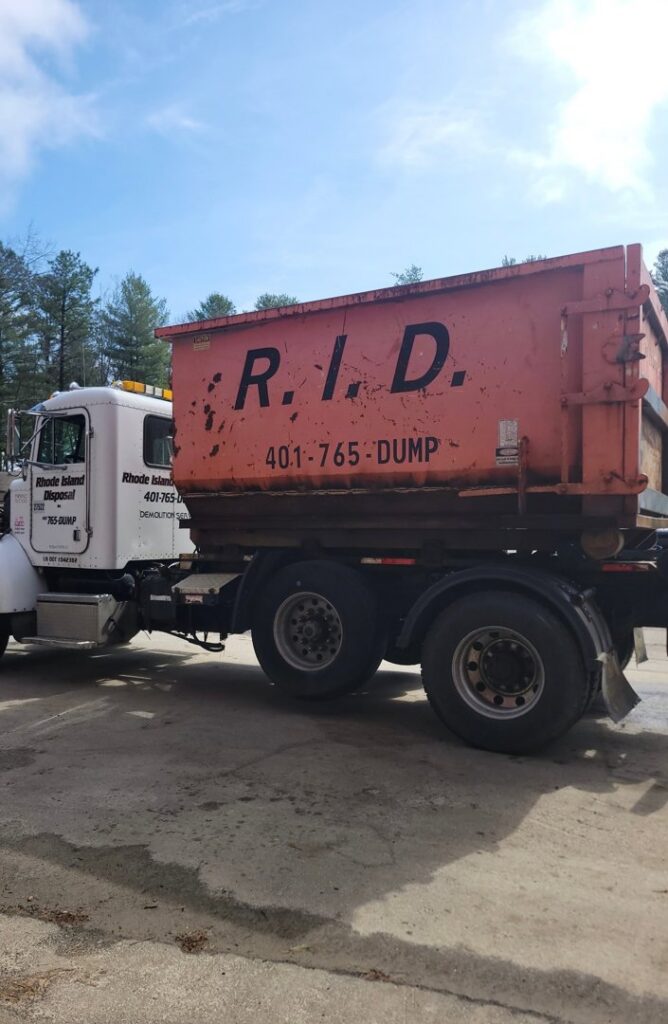 A Rhode Island Disposal truck carrying a large orange roll-off dumpster, ready for junk removal in Providence, RI.