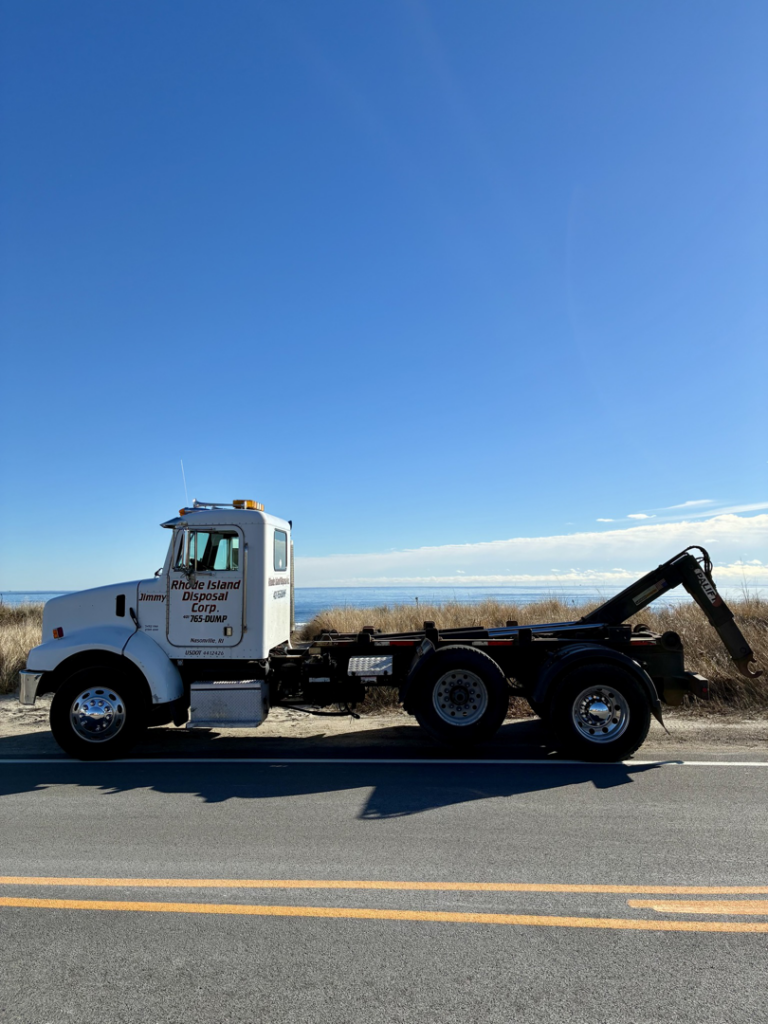 A Rhode Island Disposal roll-off truck parked by the ocean, showcasing the company's equipment in Providence, RI.