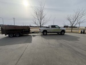 A Richie Bros Junk Removal branded pickup truck towing a large trailer, ready for a job in Urbandale, IA.