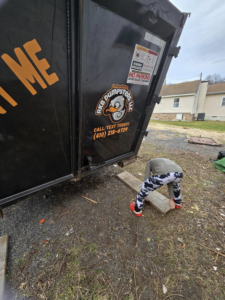 An RKB Dumpsters, LLC roll-off dumpster being carefully placed on the ground for a job in Frederick, MD.
