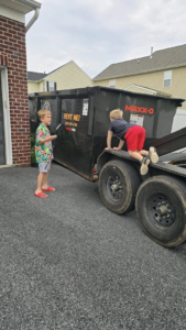 An RKB Dumpsters, LLC roll-off dumpster on a trailer parked in a residential driveway in Frederick, MD.