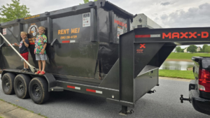A black RKB Dumpsters, LLC roll-off dumpster on a trailer being delivered in Frederick, MD.