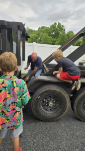 An RKB Dumpsters, LLC employee operating the mechanism of a roll-off dumpster trailer in Frederick, MD.