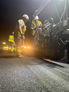 A road paving crew working at night, laying fresh asphalt for Northeast-Paving in Bangor, ME