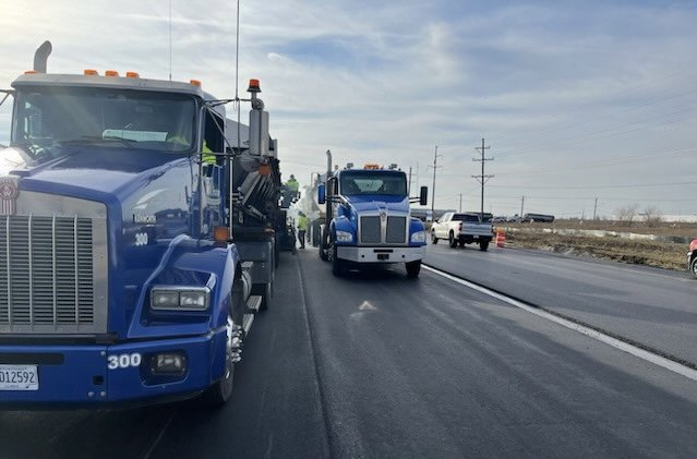 Trucks and workers performing road paving services for R A Seaton Contractor Services in Rockford, IL.