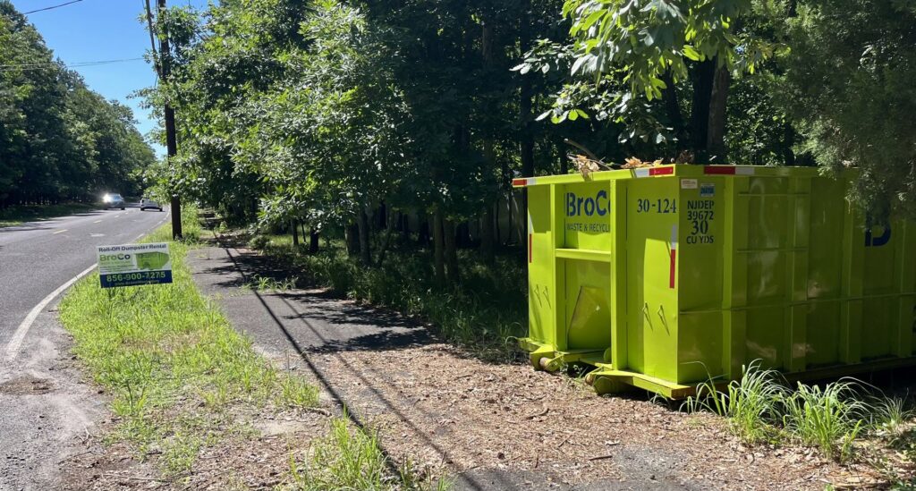 A green Broco Waste & Recycling dumpster placed by the roadside for a rental in Warminster, PA.