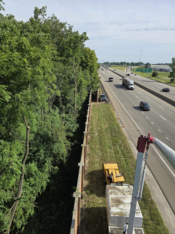 Roadside tree trimming and clearing along a highway, performed from a bucket truck by M.L tree service in Dayton, OH.