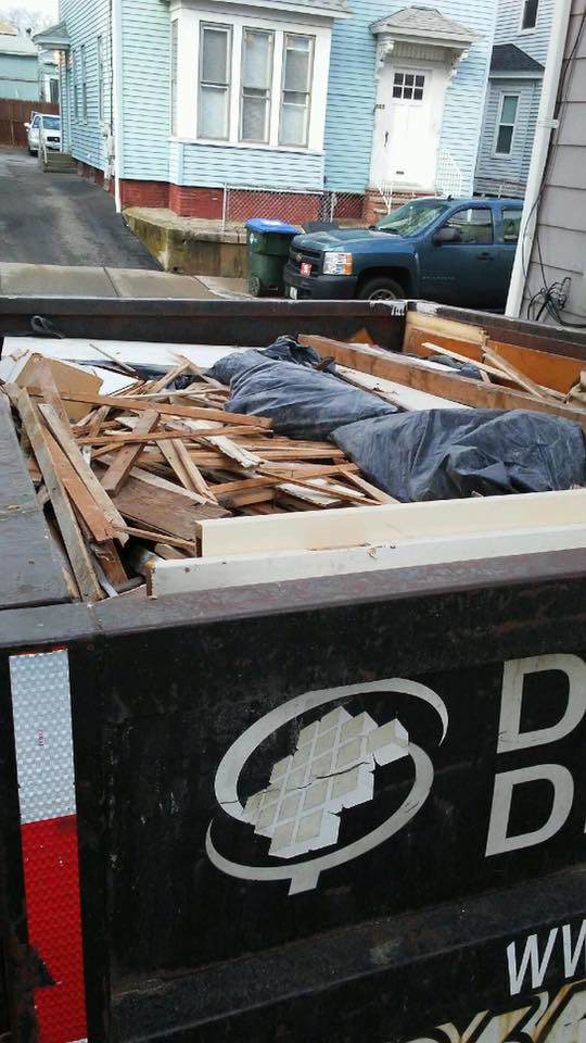 A roll-off container filled with wood scraps and debris, ready for removal by R & J Junk Removal in Warwick, RI.