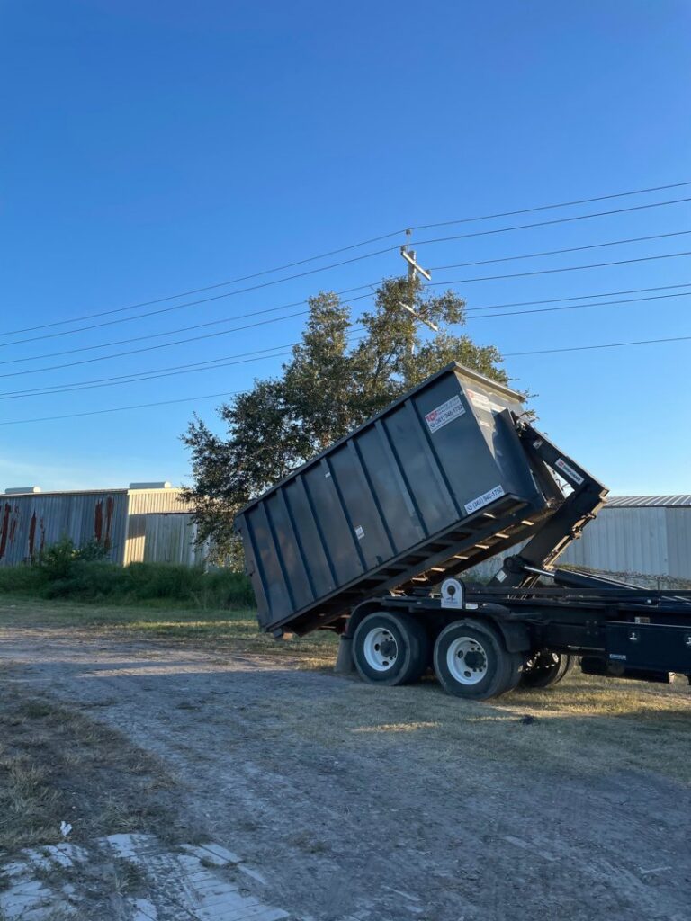 A roll-off dumpster being lifted by a truck from White Star Services LLC for junk removal in Corpus Christi, TX.