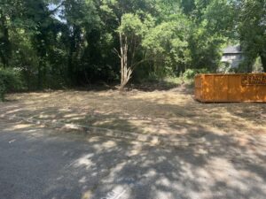 An orange roll-off dumpster from Jr's Mini Roll Off LLC on a recently cleared lot in Byron, GA.