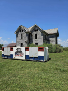 A large roll-off dumpster from Bragg About This Dump placed in front of a dilapidated house in Columbus, OH.