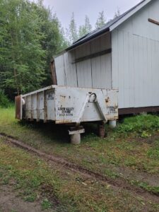A large white roll-off dumpster from Raven Valley Refuse and Recycling in Wasilla, AK, ready for junk removal.