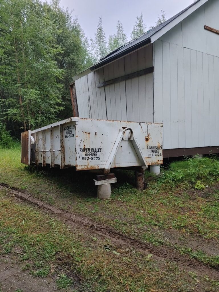 A large white roll-off dumpster from Raven Valley Refuse and Recycling in Wasilla, AK, ready for junk removal.