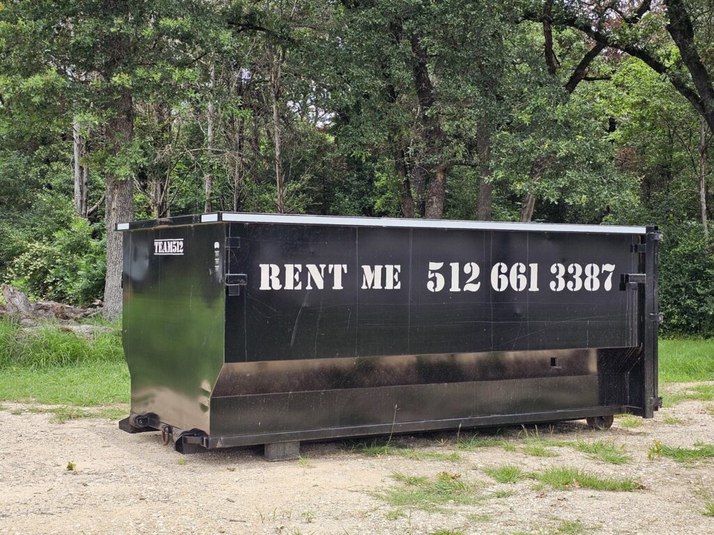 A black roll-off dumpster from Team512 with 'RENT ME' signage, available for rental in Austin, TX