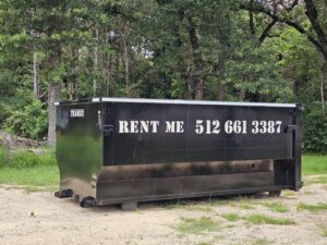A black roll-off dumpster from Team512 with 'RENT ME' signage, available for rental in Austin, TX