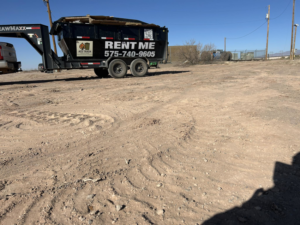 A branded roll-off dumpster trailer from Ace Trash Solutions, filled with cardboard, ready for junk removal in Las Cruces, NM.