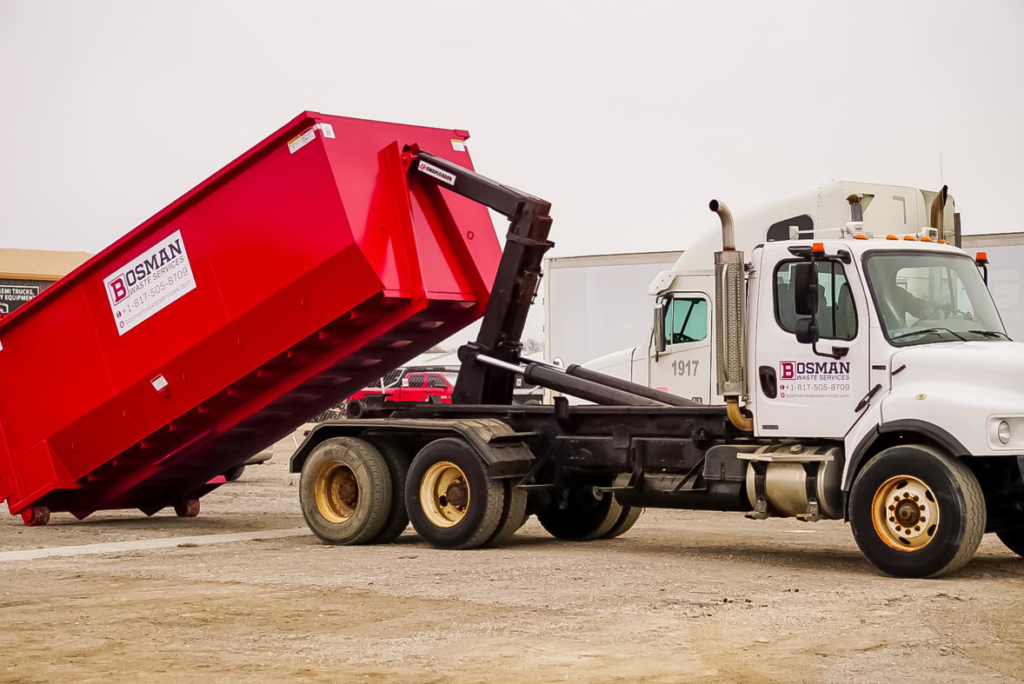 A Bosman Waste Services truck deploying a red roll-off dumpster for junk removal in Roanoke, TX.