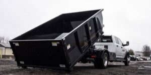 A roll-off dumpster truck delivering a black dumpster for Utah Valley Dumpsters in Provo, UT.