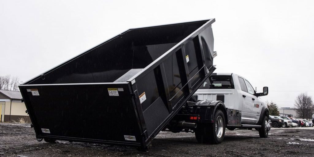 A roll-off dumpster truck delivering a black dumpster for Utah Valley Dumpsters in Provo, UT.