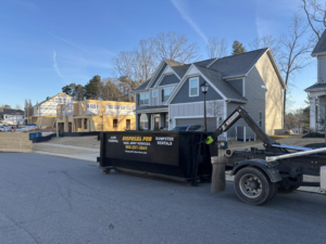 A Disposal Pro Haul Away Services truck with a roll-off dumpster in a residential neighborhood with new construction in Charlotte, NC.