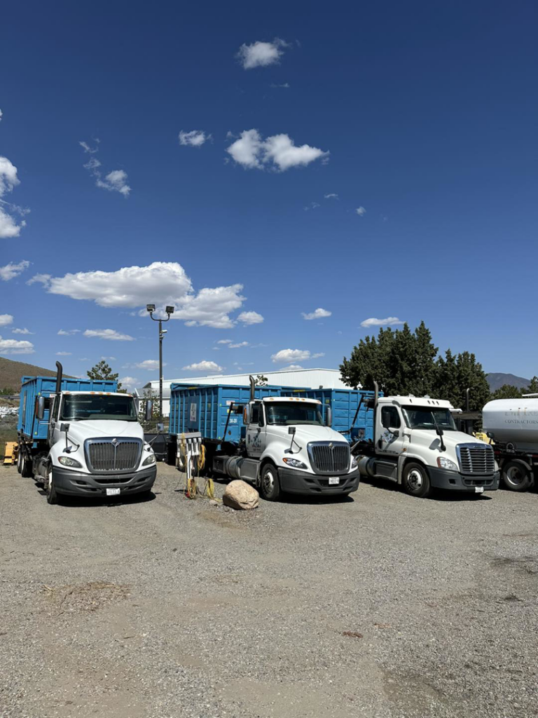 Three roll-off dumpster trucks parked in a lot, ready for junk removal services by Empire Waste Systems in Carson City, NV