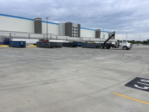 A roll-off truck with multiple dumpsters at a commercial site, providing junk removal services by A-1 Roll-Off Rentals, LLC in Baton Rouge, LA.