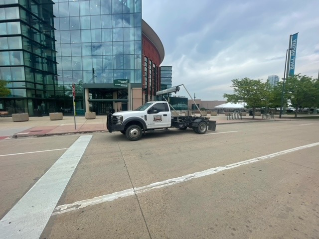A Premier Roll Off Services roll-off truck parked on a city street near Ball Arena in Thornton, CO.