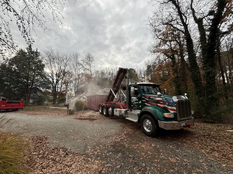 A Patuxent Roll-Off truck collecting a large pile of demolition debris at a job site in Crofton, MD