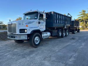 A roll-off truck with a container ready for junk removal services by East Coast Container Services LLC in Northwood, NH.