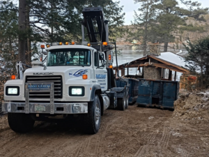 A roll-off truck with two containers at a lakeside property for East Coast Container Services LLC in Northwood, NH.