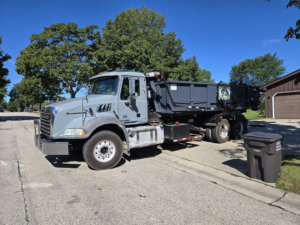 A roll-off truck delivering a dumpster on a residential street for Premier Recycling and Disposal in Waukesha, WI.