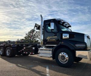A black Delta Waste Solutions roll-off truck, used for delivering and picking up junk removal dumpsters in Hattiesburg, MS.