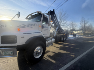 A roll-off truck deploying a container for junk removal services by East Coast Container Services LLC in Northwood, NH.