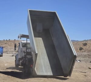 A Trash Panda roll-off truck dumping an empty dumpster, demonstrating waste management services in Carson City, NV.