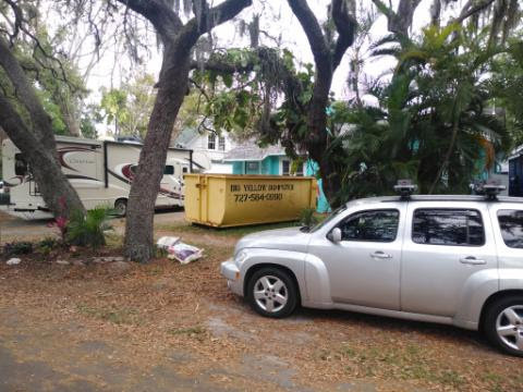 A roll-off truck with a Big Yellow Dumpster next to a pile of debris at a residential site in Saint Petersburg, FL, for a general contractor project.