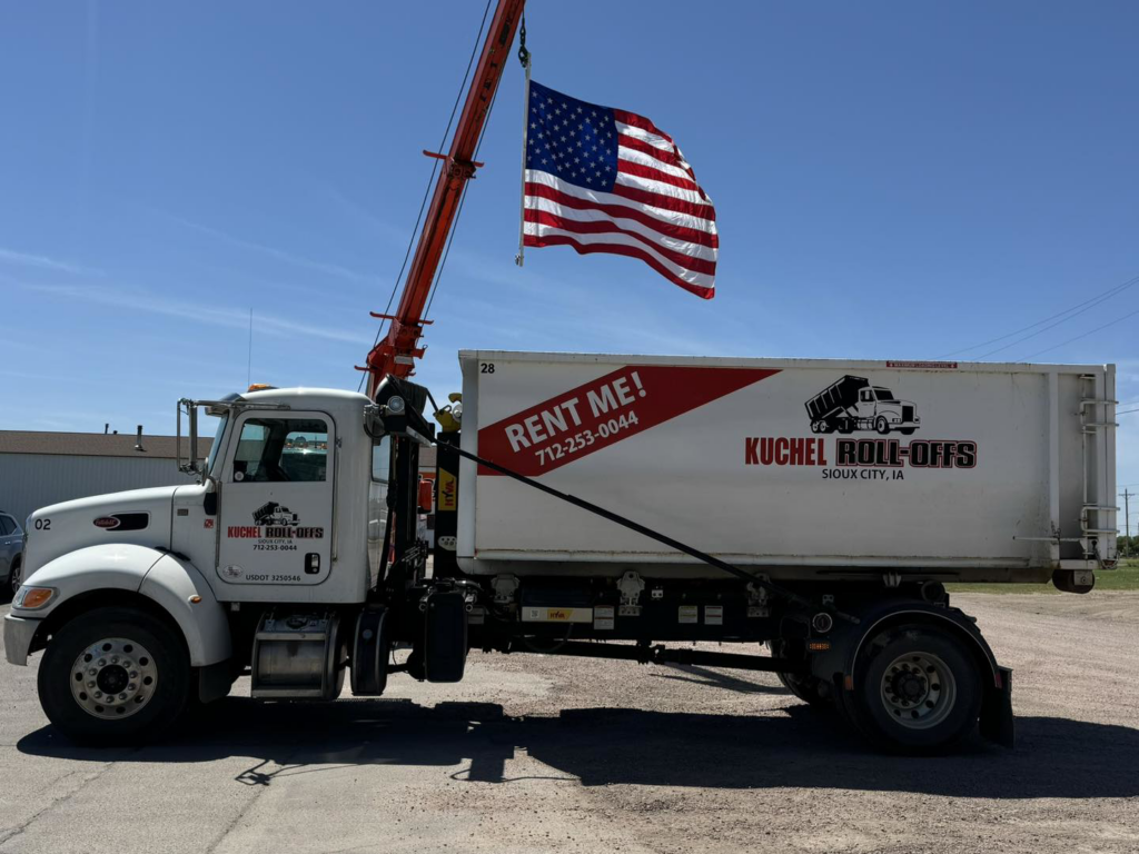 A white roll-off truck with a dumpster displaying Kuchel Roll-Offs branding in Sioux City, IA.