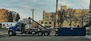 A Miedema Sanitation Inc of Huron SD roll-off truck with a blue dumpster in Mitchell, SD.
