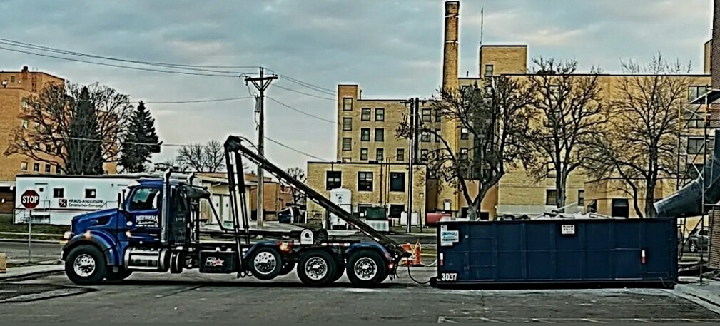 A Miedema Sanitation Inc of Huron SD roll-off truck with a blue dumpster in Mitchell, SD.
