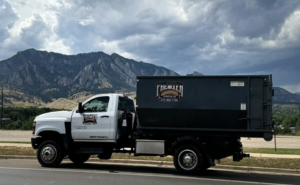 A Premier Roll Off Services truck with a dumpster parked against a mountain backdrop in Thornton, CO, ready for junk removal.