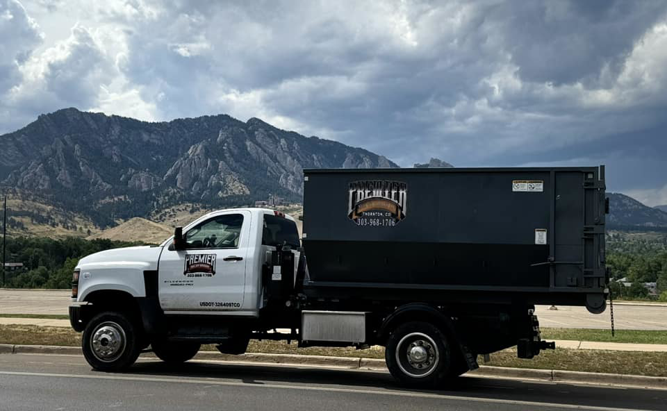 A Premier Roll Off Services truck with a dumpster parked against a mountain backdrop in Thornton, CO, ready for junk removal.