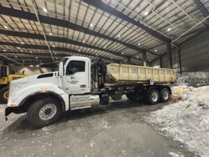 A roll-off truck with a dumpster from AT Disposal inside a recycling facility in Dewitt, IA.
