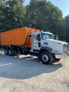 A Tenn-Scrap roll-off truck with an empty orange dumpster ready for deployment in Jackson, TN.