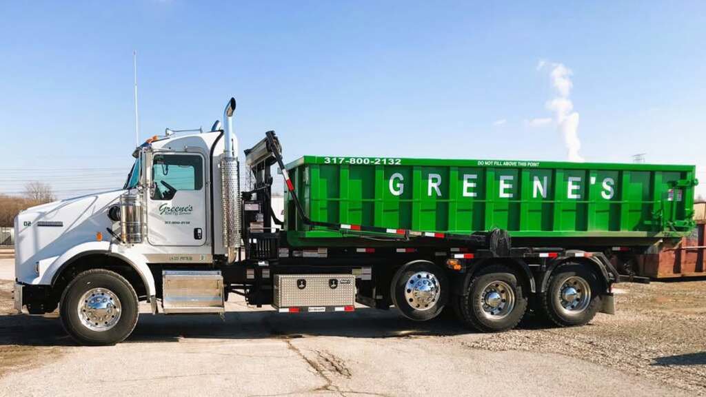 A white roll-off truck with a green dumpster from Greene's Roll Off Service in Indianapolis, IN.