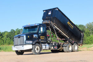 A Delta Waste Solutions roll-off truck lifting a black dumpster, demonstrating efficient junk removal services in Hattiesburg, MS.
