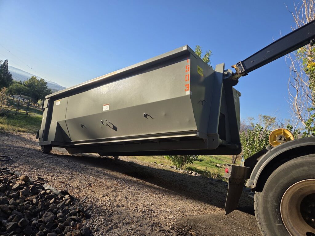 A Trash Panda roll-off truck lifting an empty dumpster, demonstrating efficient pickup services in Carson City, NV.