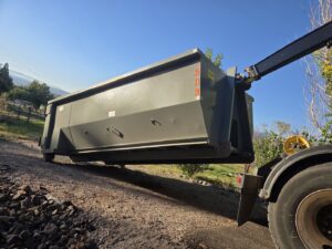 A Trash Panda roll-off truck lifting an empty dumpster, demonstrating efficient pickup services in Carson City, NV.