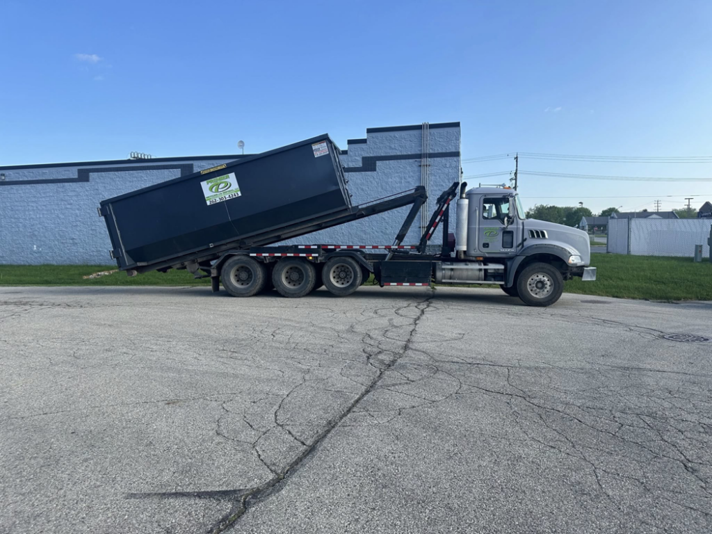 A roll-off truck in the process of loading a dumpster, demonstrating services by Premier Recycling and Disposal in Waukesha, WI.