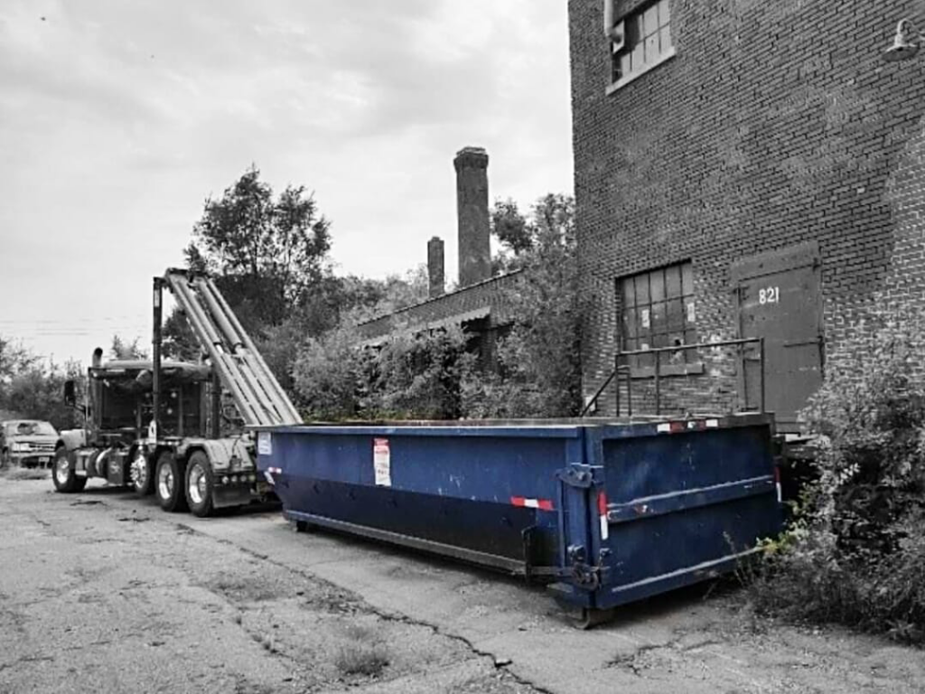 A Miedema Sanitation Inc of Huron SD roll-off truck placing a dumpster next to an old building in Mitchell, SD.
